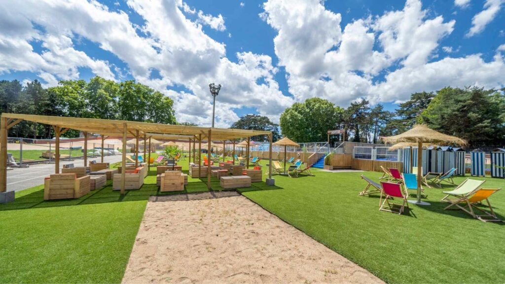 Plage en ville avec sable, mobilier, transats, parasols, piscine